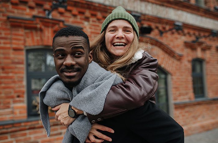 Happy couple smiling outside, woman wearing a green beanie, man with a watch. Happy couple smiling outside, woman wearing a green beanie, man with a watch.