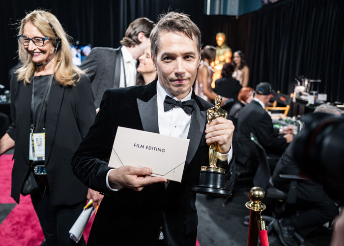 Winner holding Oscar for Film Editing, with a smile in a backstage setting at the Oscars 2025. Winner holding Oscar for Film Editing, with a smile in a backstage setting at the Oscars 2025.