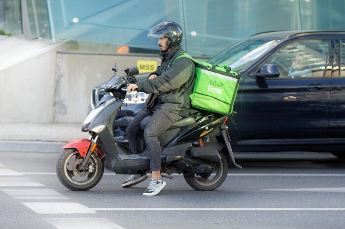 Uber Eats delivery rider on a scooter, highlighting scams that are sneakily targeting unaware victims.