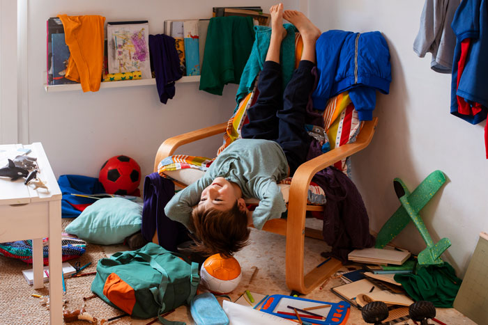 Child in a messy room with toys and clothes scattered, illustrating chaos and lack of clean surfaces. Child in a messy room with toys and clothes scattered, illustrating chaos and lack of clean surfaces.