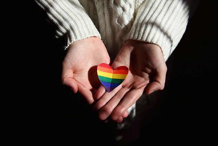 Person wearing white sweater holding a rainbow heart in hands symbolizing friend regret and best friend confession emotions. Person wearing white sweater holding a rainbow heart in hands symbolizing friend regret and best friend confession emotions.