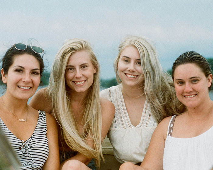 Four women smiling together on a boat during vacation, enjoying a child-free moment. Four women smiling together on a boat during vacation, enjoying a child-free moment.