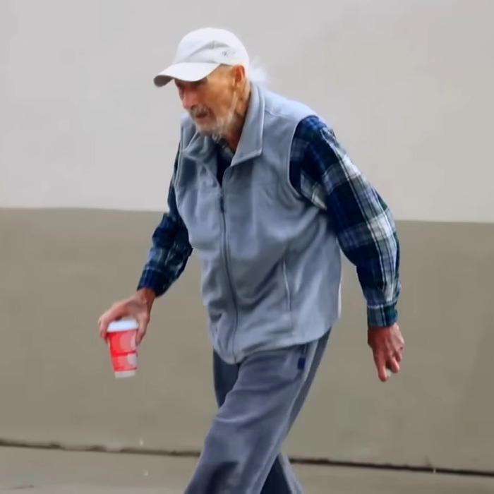 Gene Hackman in casual attire holding a cup, walking outdoors. Gene Hackman in casual attire holding a cup, walking outdoors.