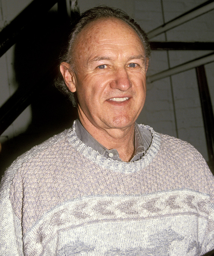 Gene Hackman in a sweater smiling at an event. Gene Hackman in a sweater smiling at an event.