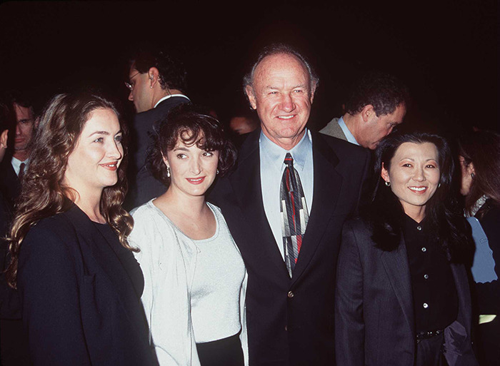Gene Hackman smiling at an event, wearing a suit and patterned tie, with Betsy Arakawa and two kids in formal attire. Gene Hackman smiling at an event, wearing a suit and patterned tie, with Betsy Arakawa and two kids in formal attire.