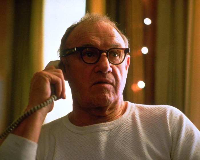 Gene Hackman wearing glasses and white long sleeve while talking to the phone indoors in a movie scene. Gene Hackman wearing glasses and white long sleeve while talking to the phone indoors in a movie scene.