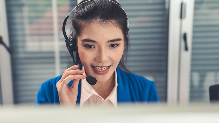 Customer service representative using a headset, engaged in a call, in a modern office setting, illustrating communication changes.