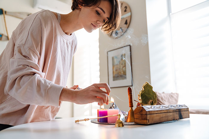 Woman lighting incense at home, engaging in a religious practice. Woman lighting incense at home, engaging in a religious practice.