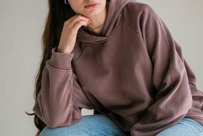 Woman in a brown hoodie and jeans looking thoughtful, illustrating relationship issues. Woman in a brown hoodie and jeans looking thoughtful, illustrating relationship issues.