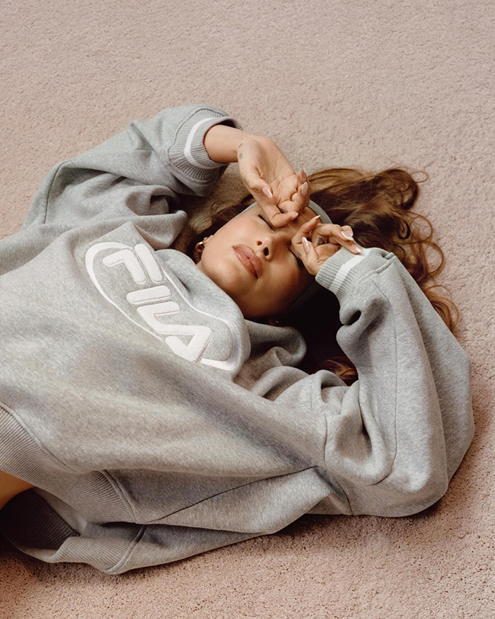 Hailey Bieber in gray sweatshirt lying on the floor, hands over face. Hailey Bieber in gray sweatshirt lying on the floor, hands over face.