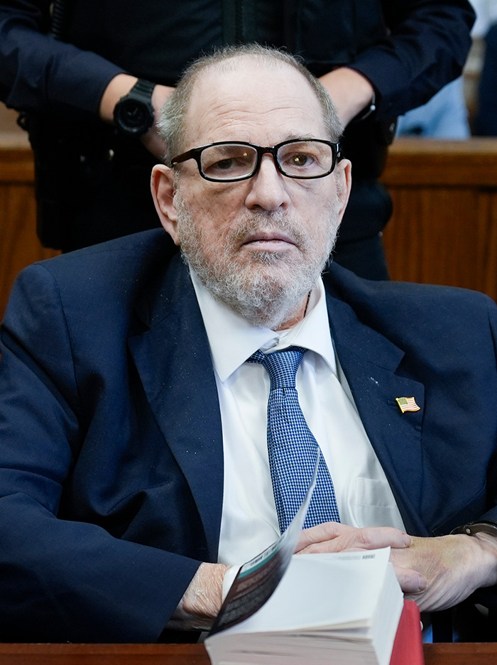 Harvey Weinstein in a suit and glasses sits in a courtroom. Harvey Weinstein in a suit and glasses sits in a courtroom.