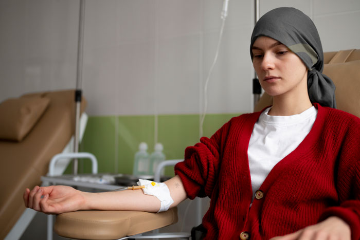 Person receiving medical treatment, wearing a red cardigan and headscarf, illustrating a serious health diagnosis. Person receiving medical treatment, wearing a red cardigan and headscarf, illustrating a serious health diagnosis.