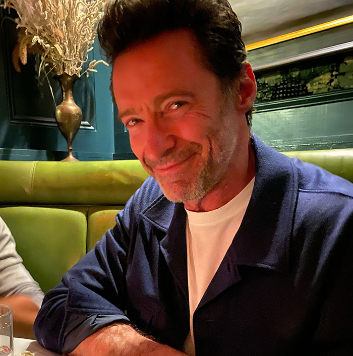 A man smiling at a restaurant, wearing a navy jacket, related to Hugh Jackman divorce news. A man smiling at a restaurant, wearing a navy jacket, related to Hugh Jackman divorce news.