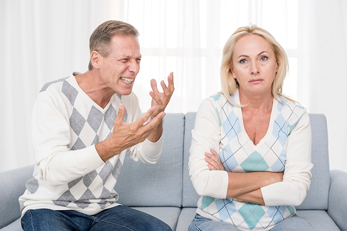 Man frustrated with woman on couch, possibly debating a gift choice, related to husband gift vacuum wife topic. Man frustrated with woman on couch, possibly debating a gift choice, related to husband gift vacuum wife topic.