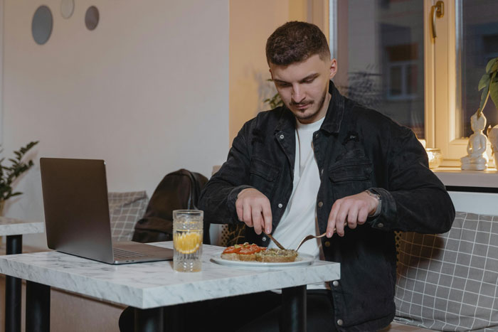 Man at cafe eating lunch with a laptop, spending money on meal and coffee. Man at cafe eating lunch with a laptop, spending money on meal and coffee.