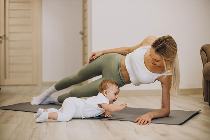 Woman doing side plank on yoga mat with baby, focusing on fitness postpartum. Woman doing side plank on yoga mat with baby, focusing on fitness postpartum.