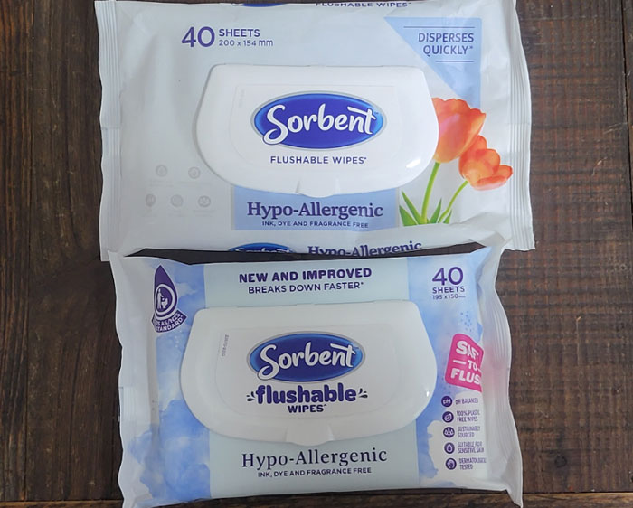 "Sorbent flushable wipes packages on wooden surface; hypo-allergenic and new version claims to break down faster."