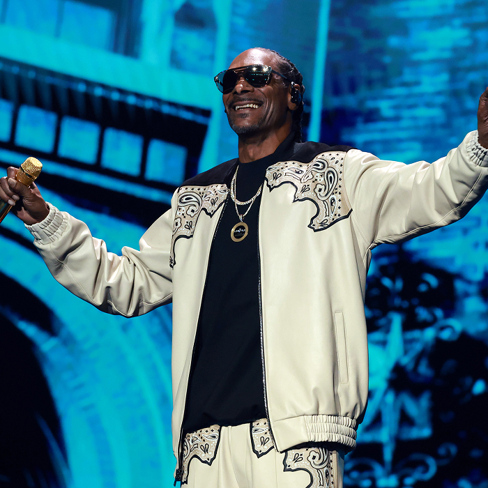Snoop Dogg performing on stage in a stylish outfit, holding a microphone, illustrating net-worth success through music and business. Snoop Dogg performing on stage in a stylish outfit, holding a microphone, illustrating net-worth success through music and business.