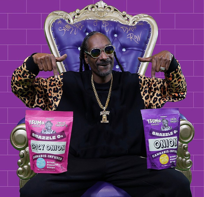 Snoop Dogg wearing a leopard-print jacket sits on a throne, showcasing Snazzle Os cannabis snacks. Snoop Dogg wearing a leopard-print jacket sits on a throne, showcasing Snazzle Os cannabis snacks.