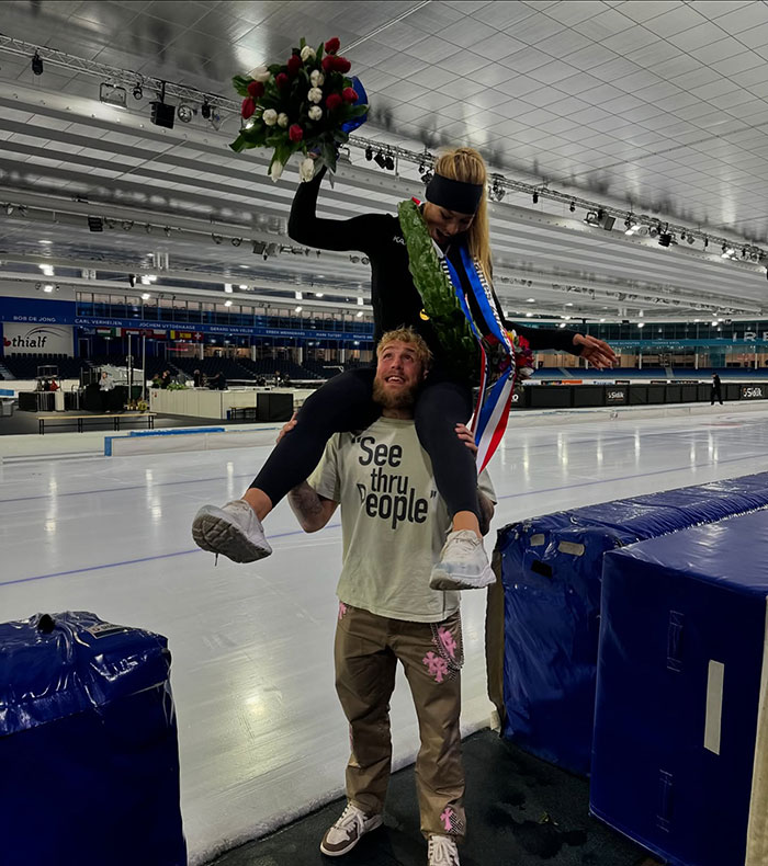 Man in arena lifting a speed skater with flowers, wearing a "See thru People" shirt. Man in arena lifting a speed skater with flowers, wearing a "See thru People" shirt.