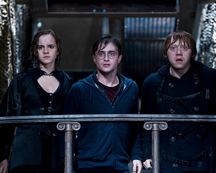 Characters from Harry Potter series look surprised and serious on a set resembling a dark chamber. Characters from Harry Potter series look surprised and serious on a set resembling a dark chamber.