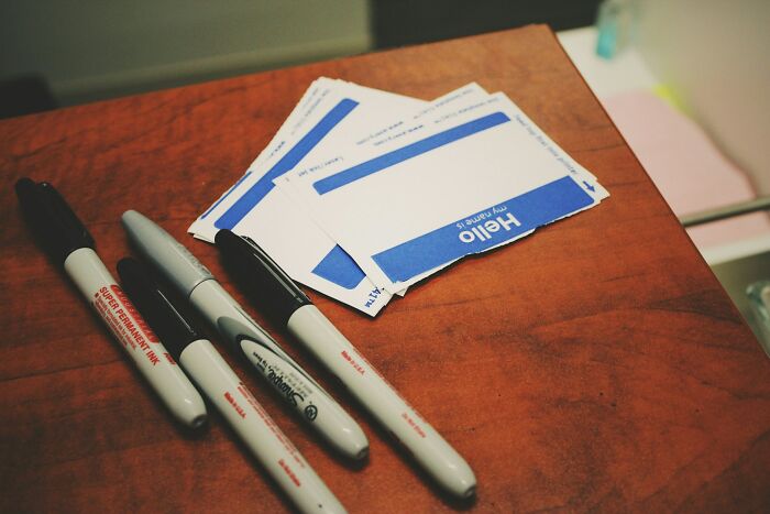 Markers and blank name tags on a wooden table, representing an insignificant thing stuck forever.