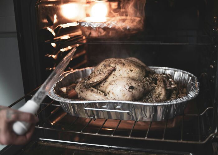Roasted chicken in an oven, embodying frugal hacks for homemade meals.