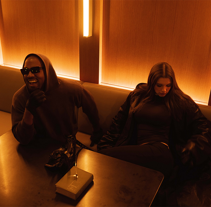 Two individuals seated in a dimly lit room wearing dark clothing. Two individuals seated in a dimly lit room wearing dark clothing.