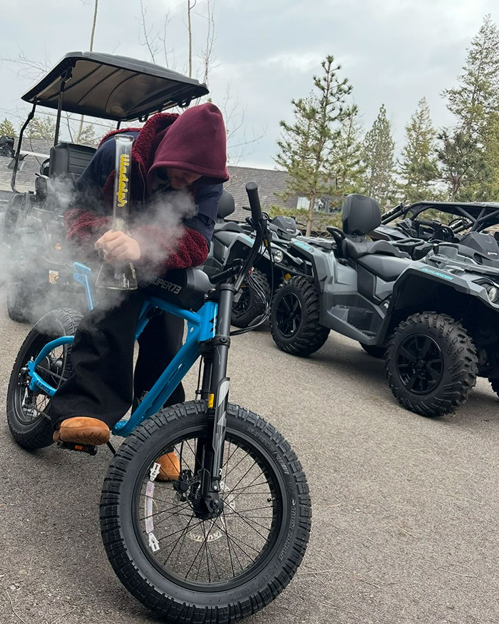 Justin Bieber smoking on a blue bike, surrounded by off-road vehicles. Justin Bieber smoking on a blue bike, surrounded by off-road vehicles.