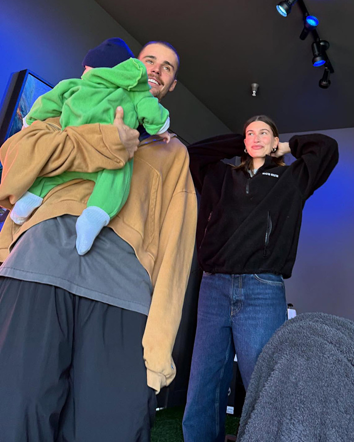 Justin Bieber holding son Jack in a casual setting, smiling, with Hailey Bieber standing nearby. Justin Bieber holding son Jack in a casual setting, smiling, with Hailey Bieber standing nearby.