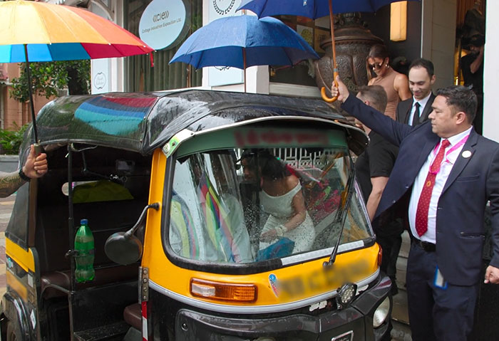 A bride and groom sit in a decorated rickshaw as people hold umbrellas, highlighting cultural contrasts with Disney's Aladdin. A bride and groom sit in a decorated rickshaw as people hold umbrellas, highlighting cultural contrasts with Disney's Aladdin.