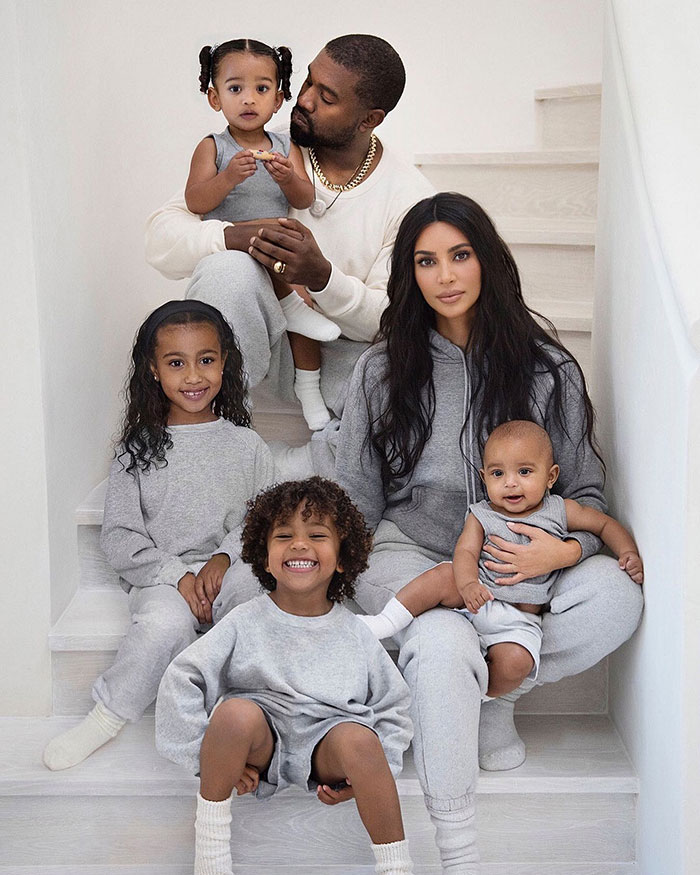 Family portrait of a couple and four children sitting on stairs in casual attire, emphasizing family dynamics and relationships. Family portrait of a couple and four children sitting on stairs in casual attire, emphasizing family dynamics and relationships.