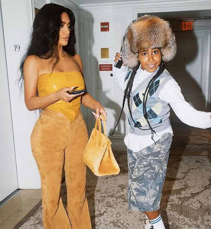 Woman in a yellow top and child in hat, indoors. They appear to be having a cheerful interaction. Woman in a yellow top and child in hat, indoors. They appear to be having a cheerful interaction.