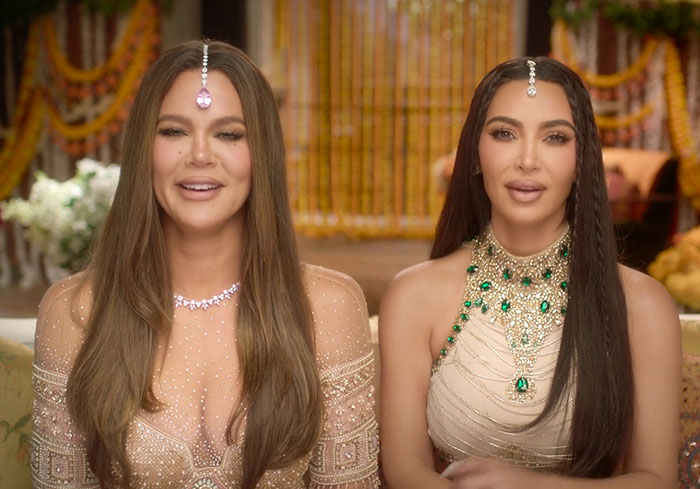 Kim Kardashian and another person wearing traditional Indian jewelry in a lavishly decorated setting. Kim Kardashian and another person wearing traditional Indian jewelry in a lavishly decorated setting.