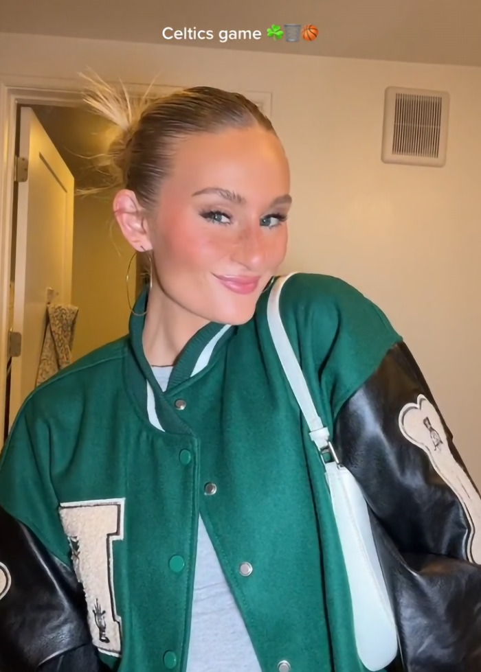 Woman in a green varsity jacket, sparking debate about the hottest outfit at a Celtics game. Woman in a green varsity jacket, sparking debate about the hottest outfit at a Celtics game.