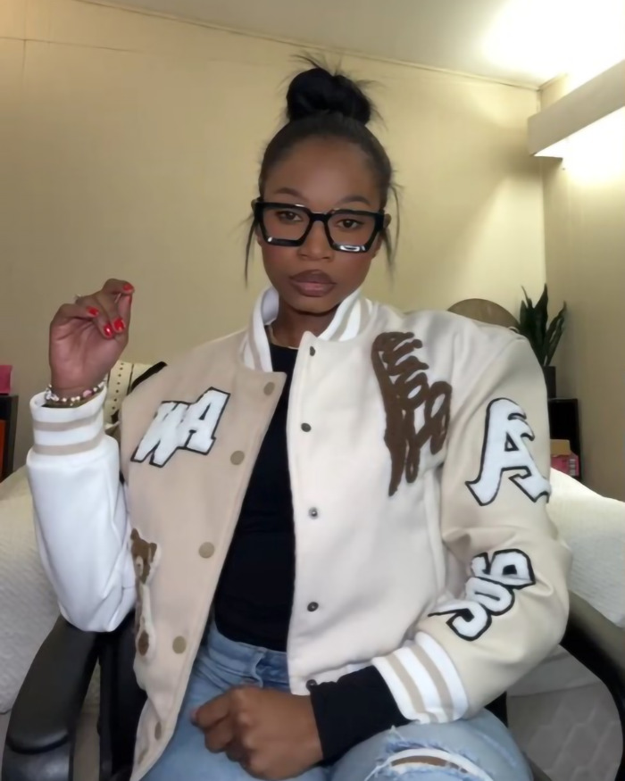 Woman wearing a varsity jacket and glasses, exemplifying a 'hottest' outfit style debate. Woman wearing a varsity jacket and glasses, exemplifying a 'hottest' outfit style debate.