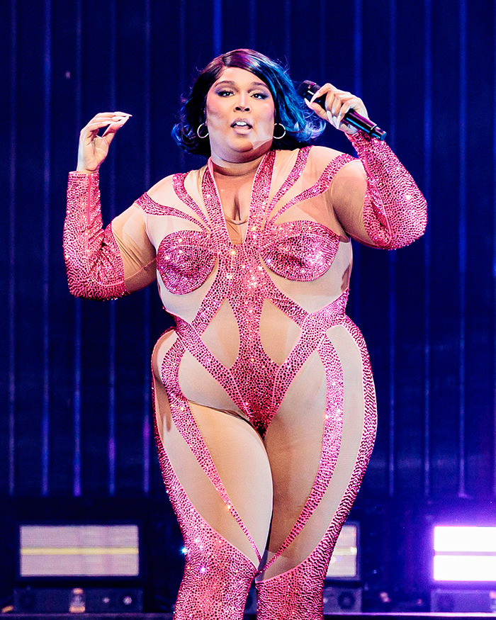 Singer in a sparkling pink bodysuit on stage, embracing body positivity and challenging obesity norms. Singer in a sparkling pink bodysuit on stage, embracing body positivity and challenging obesity norms.