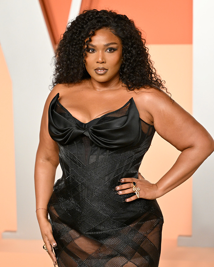 Curly-haired woman in a black dress poses confidently at an event, related to obesity discussion. Curly-haired woman in a black dress poses confidently at an event, related to obesity discussion.