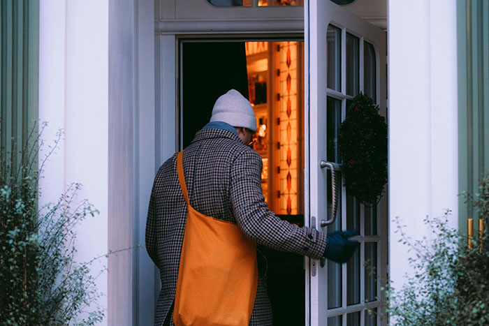 Man with an orange bag enters a warmly lit house through a glass door, conveying themes of love story deception. Man with an orange bag enters a warmly lit house through a glass door, conveying themes of love story deception.