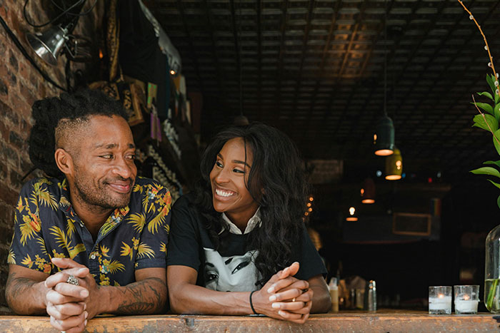 Couple at a cozy bar smiling, discussing their love story amid past challenges. Couple at a cozy bar smiling, discussing their love story amid past challenges.