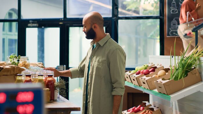 Man shopping in a supermarket, browsing produce and sauces. Man shopping in a supermarket, browsing produce and sauces.