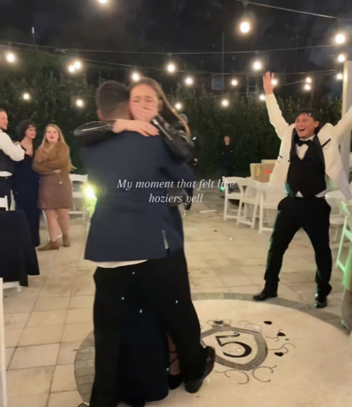 Couple embracing during a proposal at a wedding, with guests reacting in the background. Couple embracing during a proposal at a wedding, with guests reacting in the background.