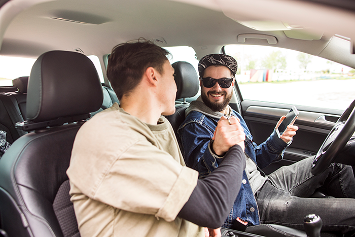 Two friends in a car sharing a handshake, symbolizing the end of free rides to work. Two friends in a car sharing a handshake, symbolizing the end of free rides to work.