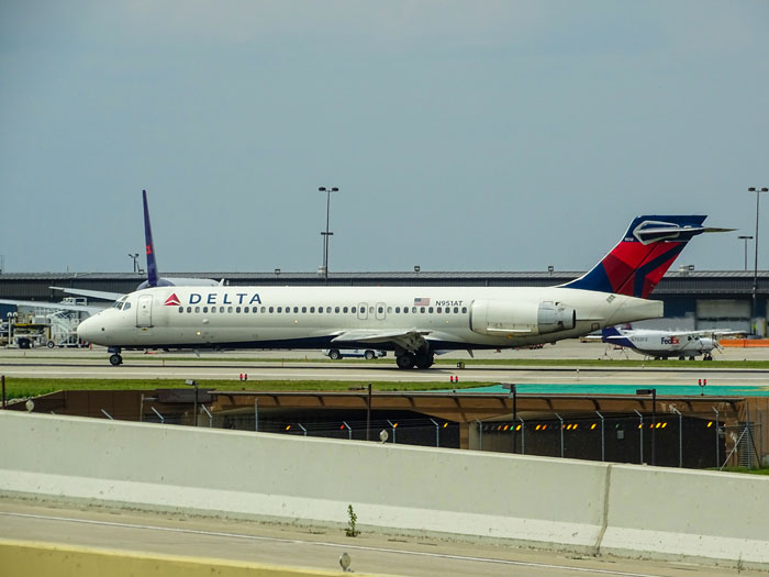 Delta Air Lines plane taxiing on runway at airport, with terminal in background, related to travel seating conflicts. Delta Air Lines plane taxiing on runway at airport, with terminal in background, related to travel seating conflicts.
