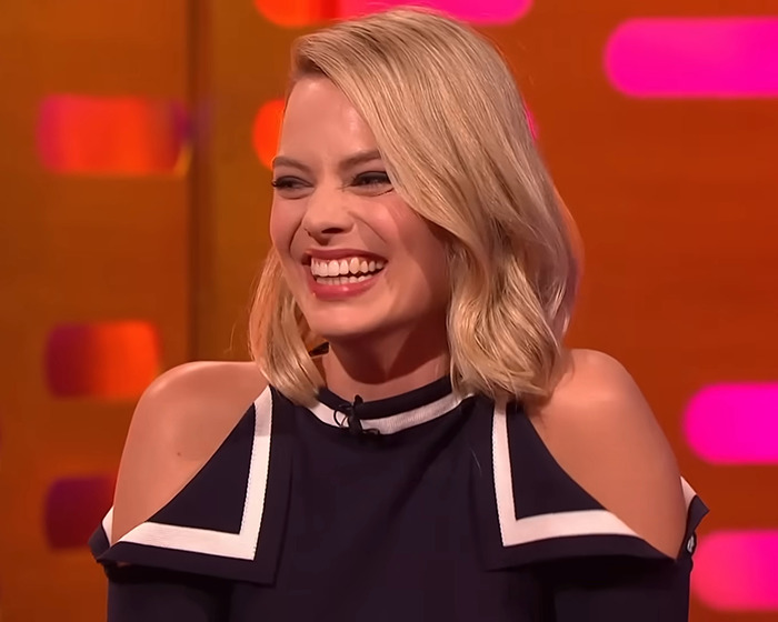 Smiling woman in a black and white top on a talk show set, associated with Wuthering Heights costume news. Smiling woman in a black and white top on a talk show set, associated with Wuthering Heights costume news.