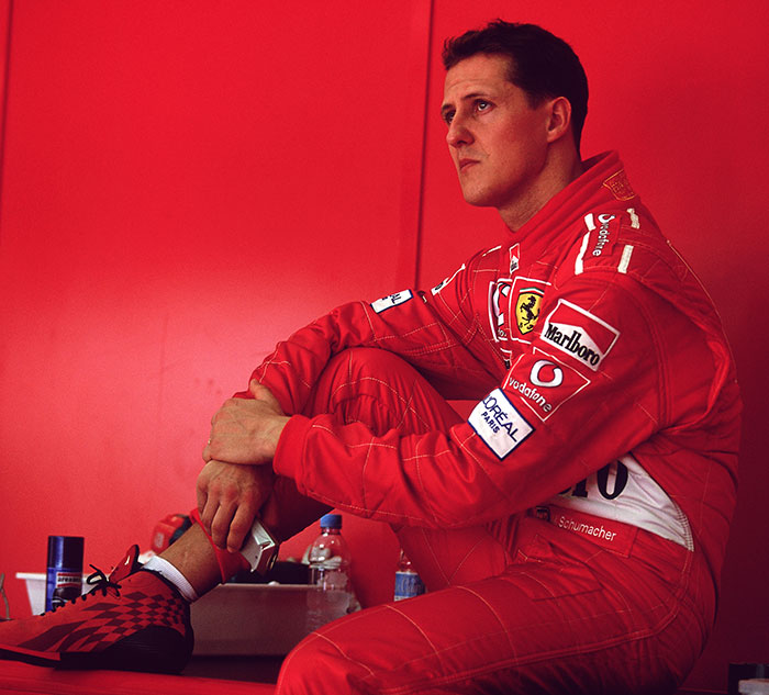 F1 Legend Michael Schumacher in Ferrari race suit seated, deep in thought. F1 Legend Michael Schumacher in Ferrari race suit seated, deep in thought.