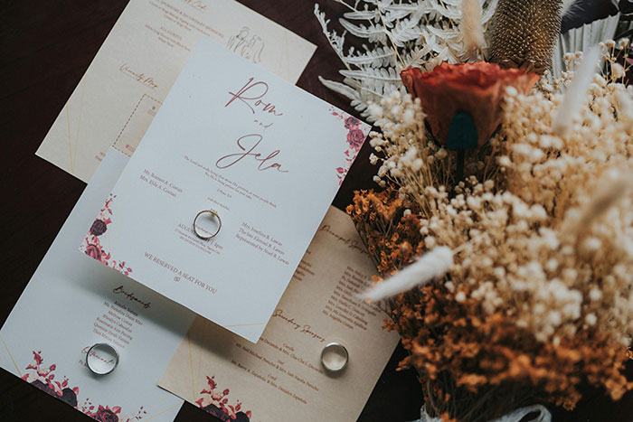 Wedding invitations with elegant design and rings, surrounded by dried flowers, reflecting mil-expectations style. Wedding invitations with elegant design and rings, surrounded by dried flowers, reflecting mil-expectations style.