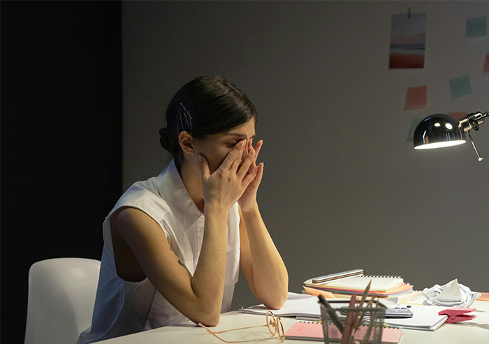 A woman sits at a desk, looking stressed while planning wedding invitations under a desk lamp. A woman sits at a desk, looking stressed while planning wedding invitations under a desk lamp.