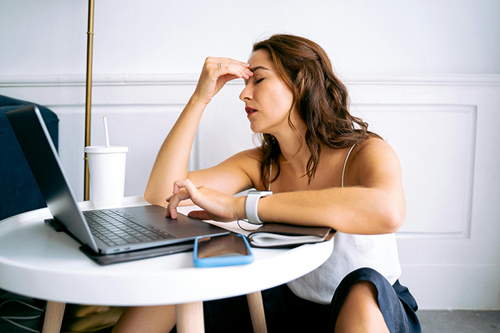 Woman stressed at a table with a laptop, planning wedding invitations and expectations. Woman stressed at a table with a laptop, planning wedding invitations and expectations.