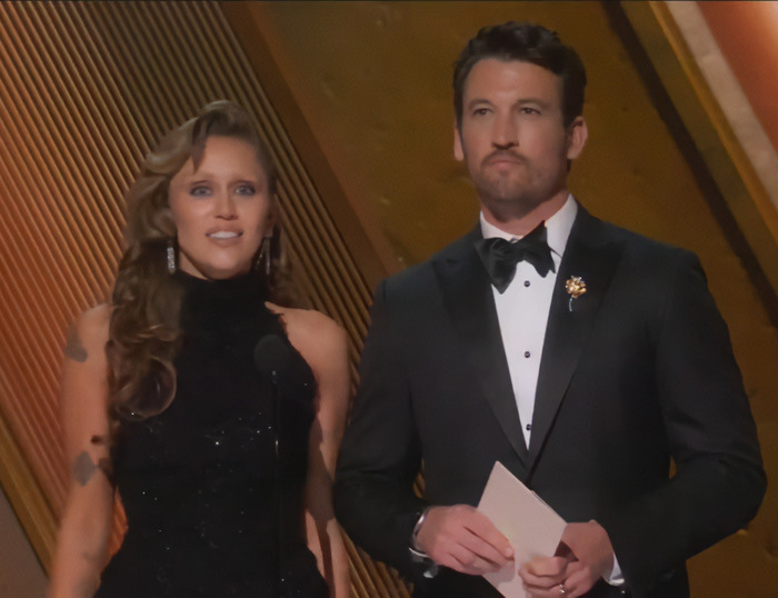Miley Cyrus and Miles Teller on stage at the Oscars, dressed in formal attire. Miley Cyrus and Miles Teller on stage at the Oscars, dressed in formal attire.